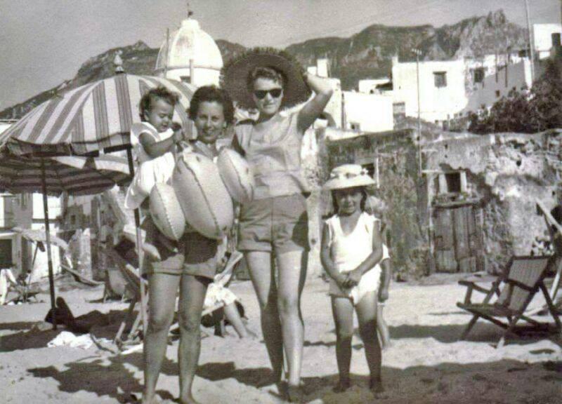 un groupe d'enfants et un adulte sur une plage entourée de parapluies et de sable