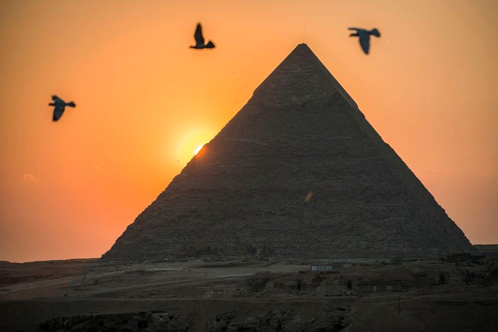 des pigeons volent dans le ciel au-dessus de la ville jumelée égyptienne de Gizeh le 21 février 2021, avec la pyramide de Khéphren en arrière-plan, une ancienne tradition transmissible de génération en génération, la pratique de la domestication des pigeons s'étend à travers les frontières des rives du Nil au nord de l'Afrique et au-delà, avec des gens non seulement en train d'entraîner des oiseaux pour des compétitions, mais aussi de les servir comme une délicatesse culinaire. Photo de Khaled Desouki AFP, par Khaled Desouki AFP via Getty Images