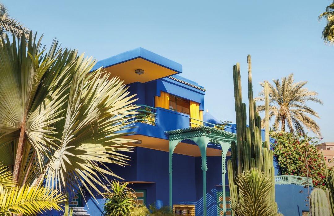 un bâtiment bleu et jaune avec des palmiers et un ciel bleu