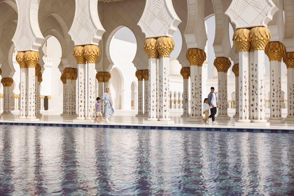 des gens marchant dans un grand bâtiment avec la mosquée cheikh zayed en arrière-plan