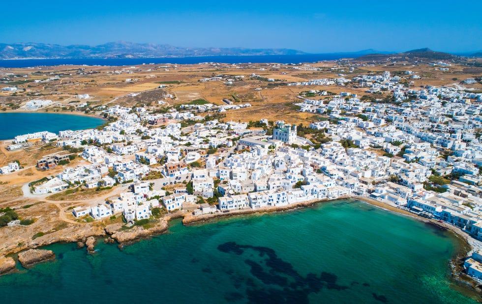 point de vue aérien de la ville de Naoussa avec ses maisons blanches typiques au bord de la mer et de petites montagnes à l'horizon, île de Paros, Grèce