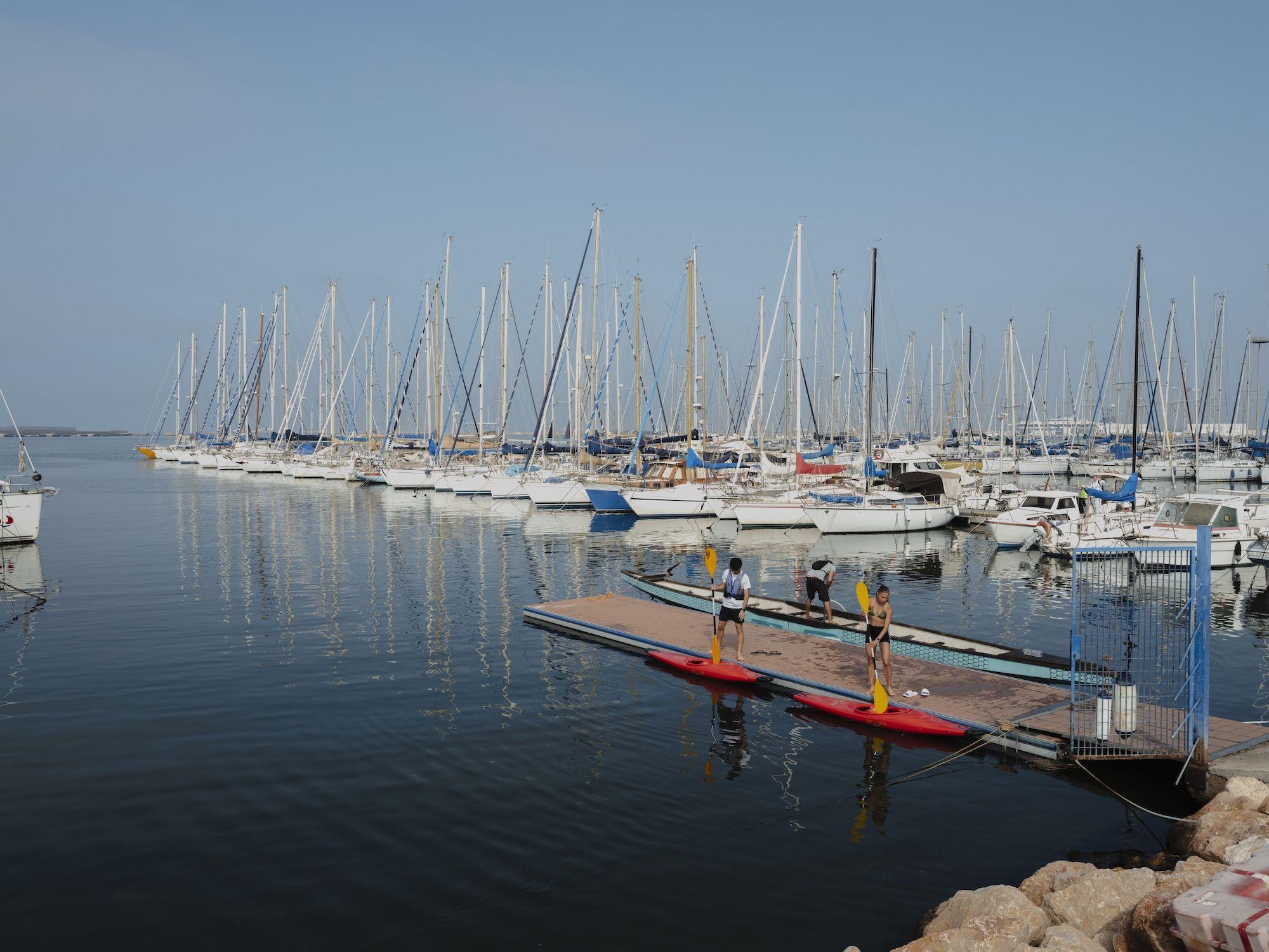 marina di cagliari avec des voiliers et des personnes préparant à faire du paddle