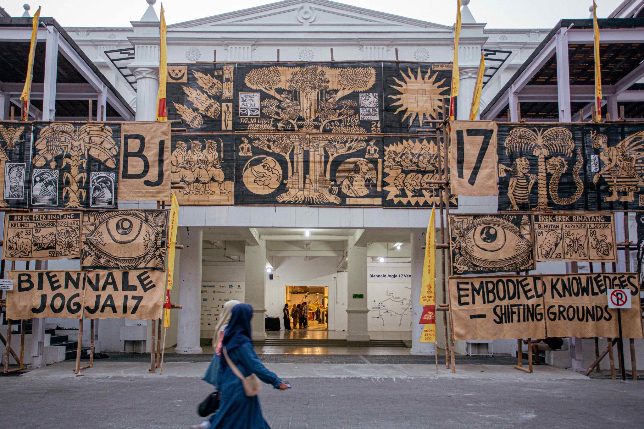 une personne marchant devant un bâtiment avec des graffitis dessus