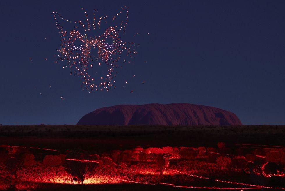 un feu d'artifice explosant dans le ciel avec Uluru en arrière-plan