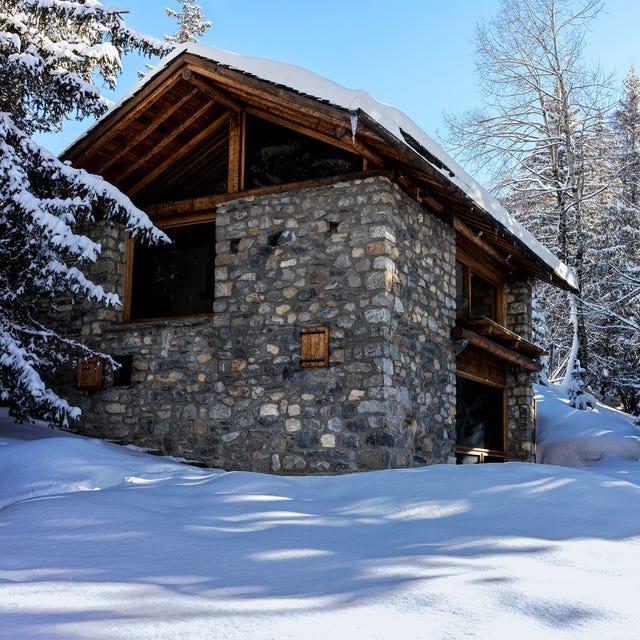 extérieur d'une maison en pierre avec des pignons en bois entourée d'un paysage enneigé