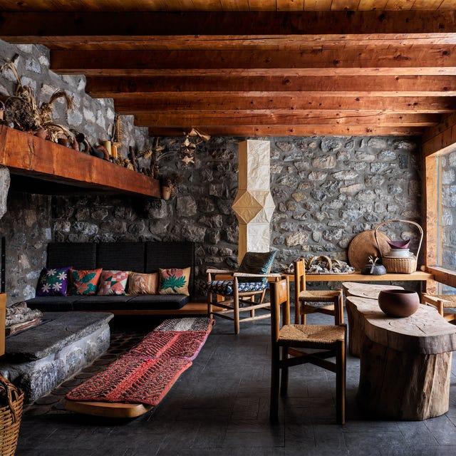 une pièce avec une cheminée et des chaises et un plafond à poutres et des murs en pierre grise ornée de galets